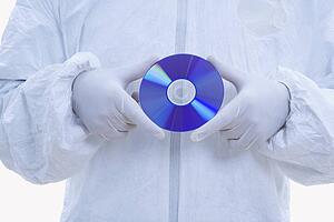 biohazard suit and latex gloves holding compact disc