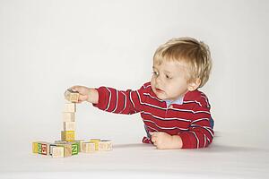 Studio portrait of young boy playing with toy blocks.