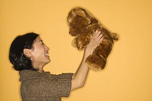 Woman holding brown teddy bear and smiling