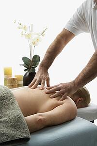 Massage therapist massaging back of woman lying on massage table