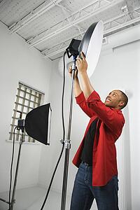 male adjusting studio lights