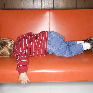 Boy sleeping on vinyl sofa