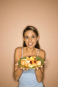 Portrait of young adult woman holding a plate of fruit