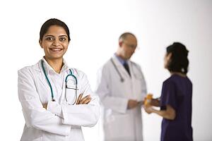 Indian mid adult woman doctor standing with medical staff in background.