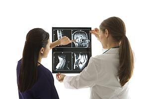 Caucasian and Asian Chinese mid-adult female doctors analyzing x-ray. 