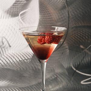 Martini with raspberry fruit against textured metallic background
