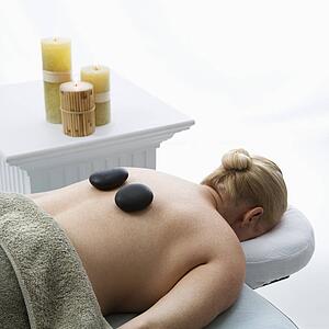 Woman lying on massage table with hot stones on her back