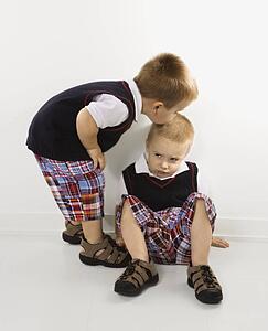 Twin boy kissing other twin boy on head