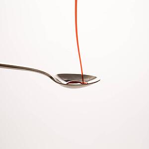 Stream of red cough syrup being poured into spoon