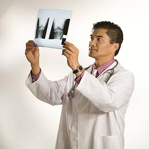 Asian American male doctor examining x-ray.