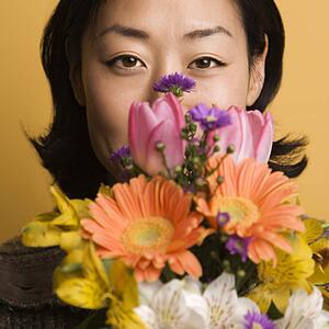 Woman holding bouquet of flowers up to face