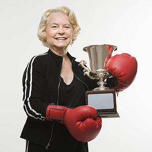 Woman wearing boxing gloves holding trophy