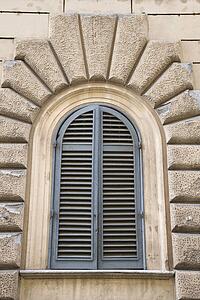 Arched window with closed shutters in Rome, Italy