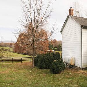 House in rural setting in Autumn with standing oil tank outside