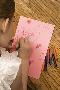Young child drawing on paper with crayons
