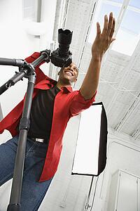 Young male adult photographer with camera gesturing