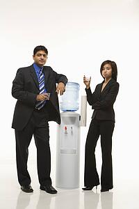Business people standing at water cooler 