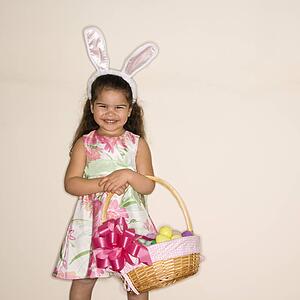 Girl wearing bunny ears holding Easter basket smiling 