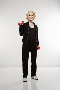 Senior woman holding dumbbells smiling at viewer