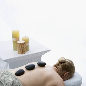 Woman lying on massage table with hot stones on her back