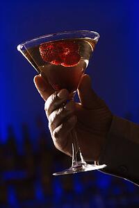 Martini with raspberry fruit against glowing blue background