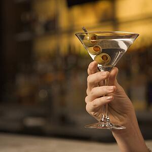Mid adult woman's hand holding a martini with three olives