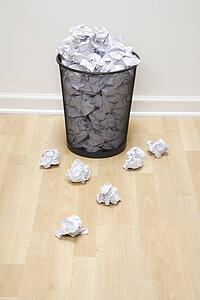 Full wire mesh trash can with crumpled paper scattered around