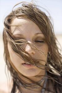 Portrait of Caucasian mid-adult woman with hair blowing across face.