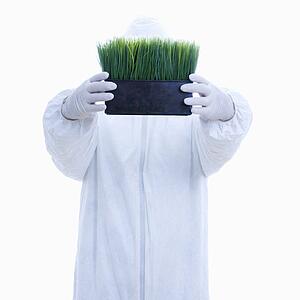 Man in biohazard suit holding pot of grass 