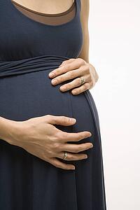 Caucasion mid-adult pregnant woman with hands on belly.