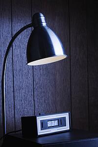 Dim desk lamp and retro clock against wood paneling at night