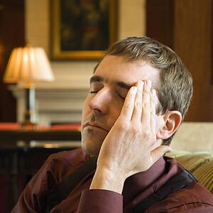 Businessman with hand to head and eyes closed