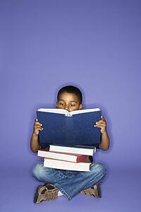 African American male child sitting with books.