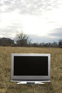 Flat screen television set in grassy field