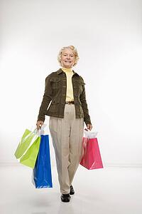Senior woman holding gift bags smiling at viewer