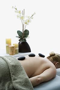 Woman lying on massage table with hot stones on her back