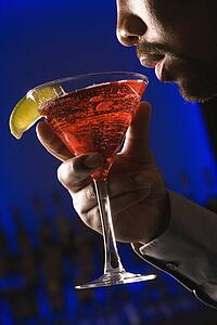 Man bringing martini up to lips in bar 
