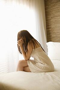 Woman sitting on bed wearing nightgown