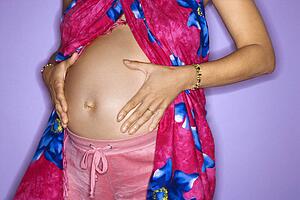 Expecting female with hands on stomach 