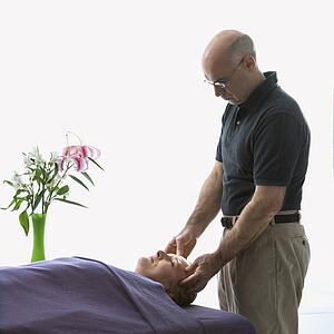 Massage therapist massaging face of woman lying on massage table