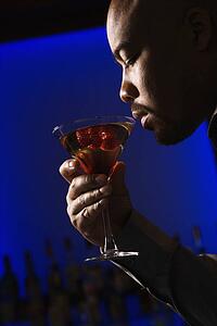 Man drinking martini in bar against glowing