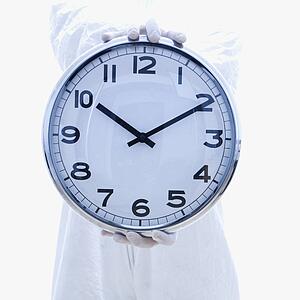 Man in biohazard suit holding out clock standing 