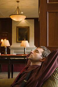 Businessman reclining with arms behind head and eyes closed