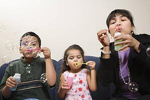 Family sitting together blowing soap bubbles.