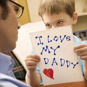 Caucasian boy giving mid adult father a drawing.