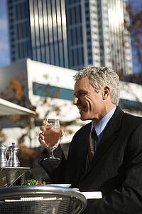 Man in suit sitting outside drinking water