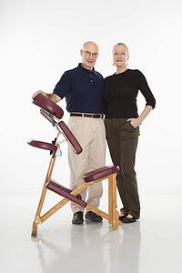 Massage therapist standing with arm around woman beside massage chair