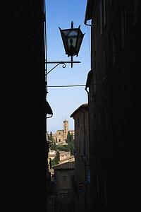 Street lamp and Siena buildings seen through darkened alley.