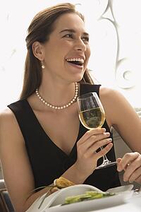 Woman smiling and drinking white wine in restaurant