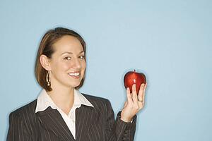 Businesswoman smiling holding red apple